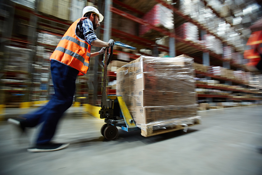 Warehouse worker pushing pallet jack showing optimized workforce production